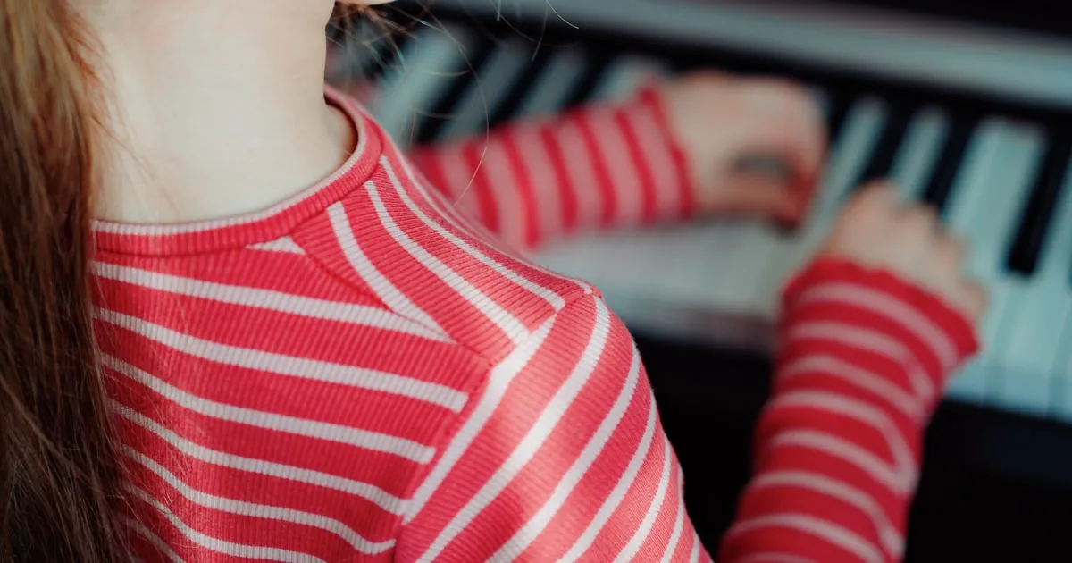 A young pianist at the keyboard with sheet music in front of her