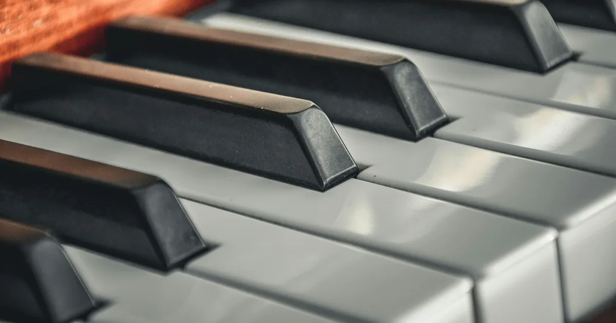 A close-up of white and black piano keys lit by soft light.