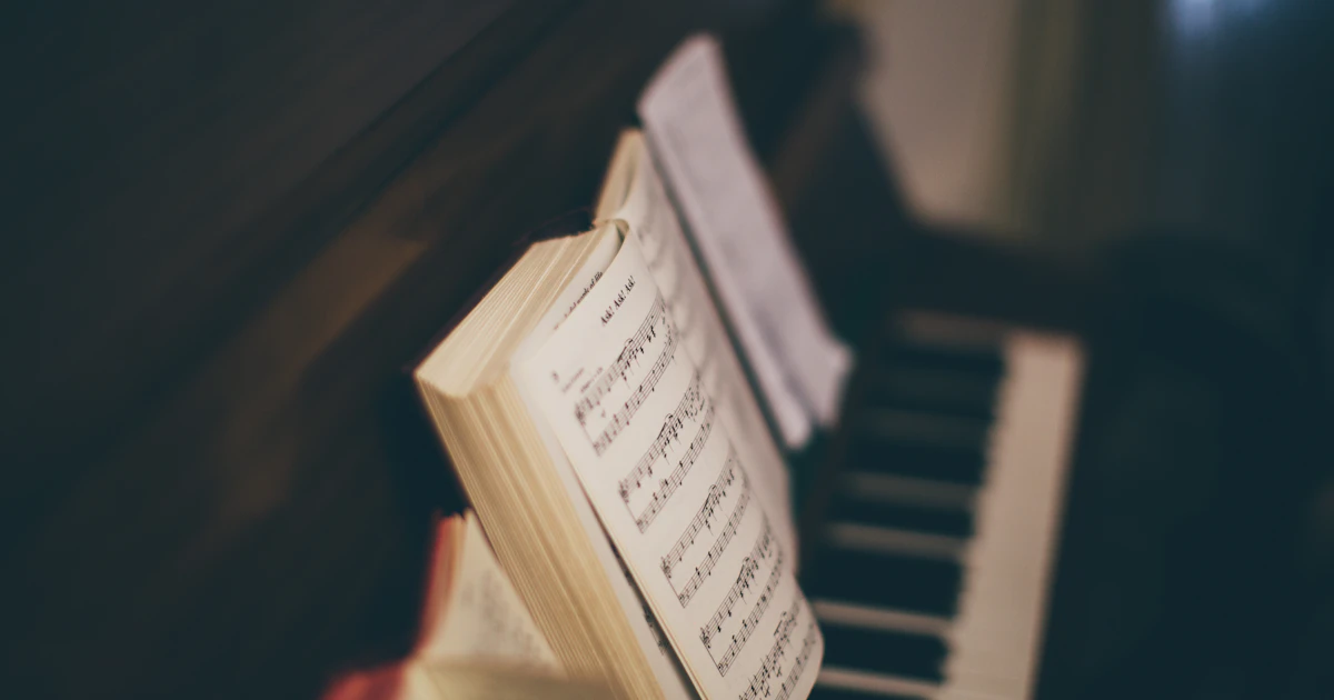 An opened music sheet book resting on top of an upright piano